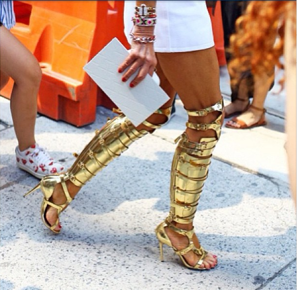 Auksu spindintys Tom Ford gladiatoriaus batai puošia mados savaitės viešnios kojas.